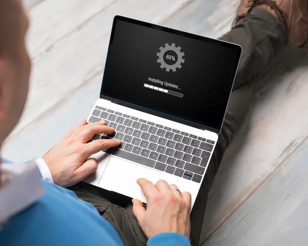Opieka nad stroną WordPress -Mężczyzna trzymający laptop na kolanach i robiący aktualizację systemu