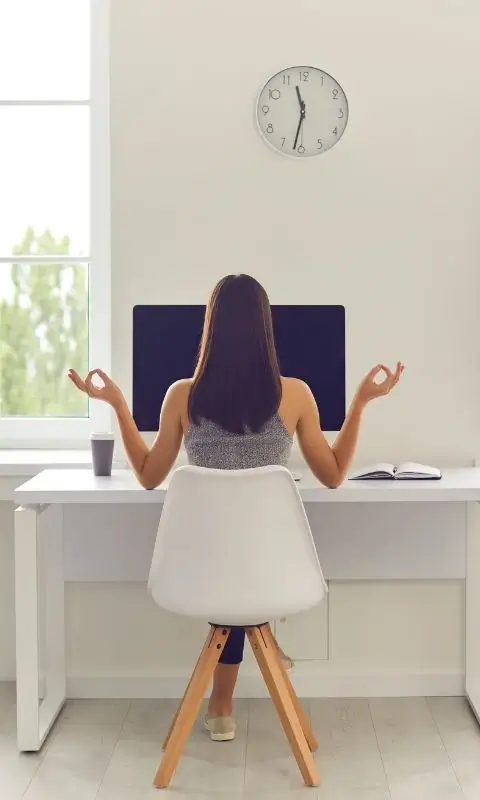 Kobieta medytująca przy biurku przed komputerem