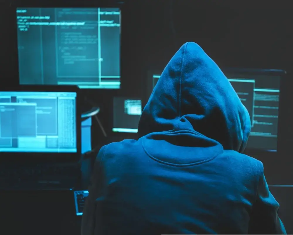 Zakapturzony mężczyzna przy monitorach,