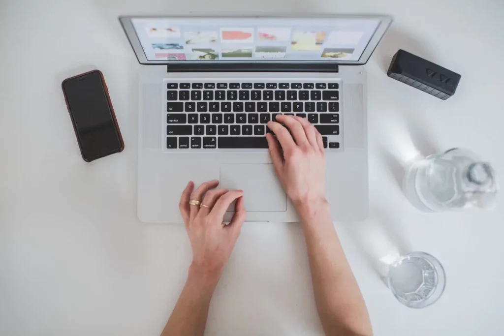 Widok z góry na ręce stukające w klawiaturę laptopa